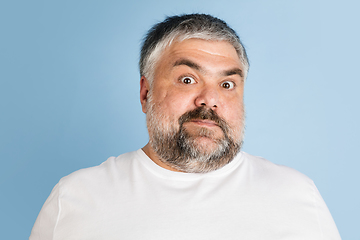 Image showing Handsome caucasian plus size male model isolated on blue studio background. Concept of inclusion, human emotions, facial expression