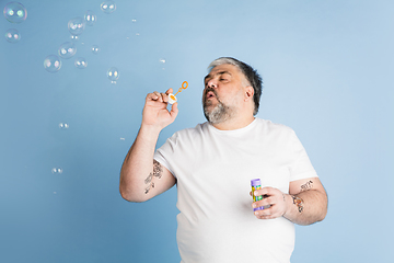 Image showing Handsome caucasian plus size male model isolated on blue studio background. Concept of inclusion, human emotions, facial expression