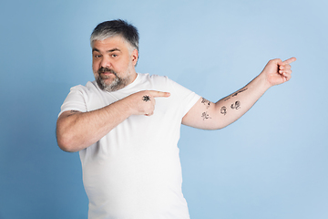 Image showing Handsome caucasian plus size male model isolated on blue studio background. Concept of inclusion, human emotions, facial expression