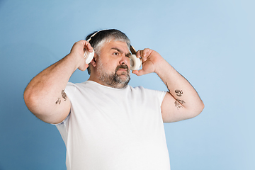 Image showing Handsome caucasian plus size male model isolated on blue studio background. Concept of inclusion, human emotions, facial expression