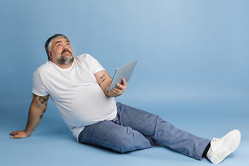 Image showing Handsome caucasian plus size male model isolated on blue studio background. Concept of inclusion, human emotions, facial expression