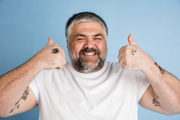 Image showing Handsome caucasian plus size male model isolated on blue studio background. Concept of inclusion, human emotions, facial expression