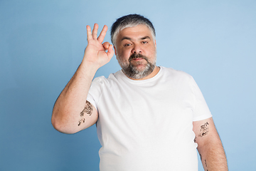 Image showing Handsome caucasian plus size male model isolated on blue studio background. Concept of inclusion, human emotions, facial expression