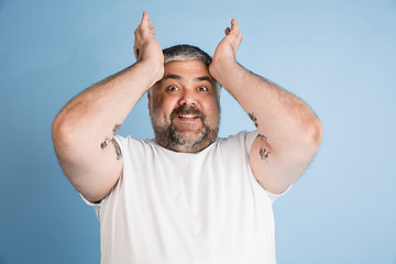 Image showing Handsome caucasian plus size male model isolated on blue studio background. Concept of inclusion, human emotions, facial expression