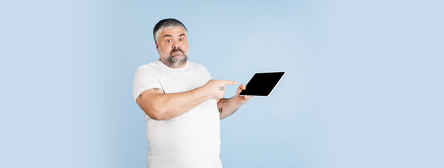 Image showing Handsome caucasian plus size male model isolated on blue studio background. Concept of inclusion, human emotions, facial expression