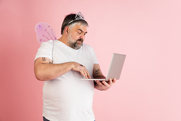 Image showing Handsome caucasian plus size male model isolated on coral pink studio background. Concept of inclusion, human emotions, facial expression