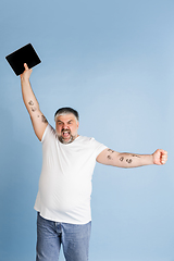 Image showing Handsome caucasian plus size male model isolated on blue studio background. Concept of inclusion, human emotions, facial expression