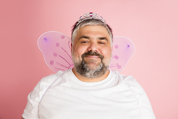 Image showing Handsome caucasian plus size male model isolated on coral pink studio background. Concept of inclusion, human emotions, facial expression