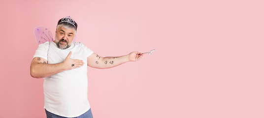 Image showing Handsome caucasian plus size male model isolated on coral pink studio background. Concept of inclusion, human emotions, facial expression