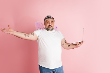 Image showing Handsome caucasian plus size male model isolated on coral pink studio background. Concept of inclusion, human emotions, facial expression