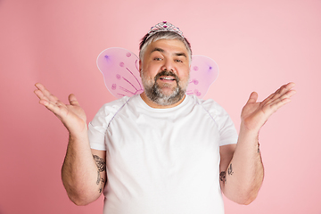 Image showing Handsome caucasian plus size male model isolated on coral pink studio background. Concept of inclusion, human emotions, facial expression