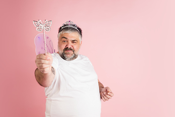 Image showing Handsome caucasian plus size male model isolated on coral pink studio background. Concept of inclusion, human emotions, facial expression