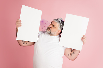 Image showing Handsome caucasian plus size male model isolated on coral pink studio background. Concept of inclusion, human emotions, facial expression