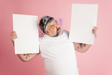 Image showing Handsome caucasian plus size male model isolated on coral pink studio background. Concept of inclusion, human emotions, facial expression