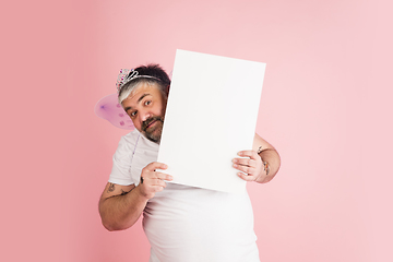 Image showing Handsome caucasian plus size male model isolated on coral pink studio background. Concept of inclusion, human emotions, facial expression