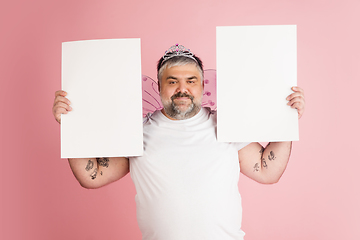 Image showing Handsome caucasian plus size male model isolated on coral pink studio background. Concept of inclusion, human emotions, facial expression