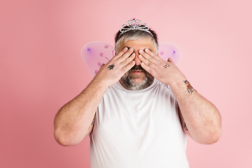 Image showing Handsome caucasian plus size male model isolated on coral pink studio background. Concept of inclusion, human emotions, facial expression