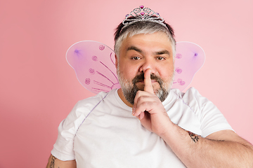 Image showing Handsome caucasian plus size male model isolated on coral pink studio background. Concept of inclusion, human emotions, facial expression