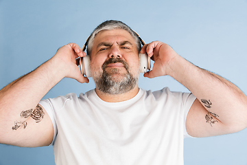 Image showing Handsome caucasian plus size male model isolated on blue studio background. Concept of inclusion, human emotions, facial expression