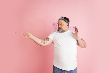 Image showing Handsome caucasian plus size male model isolated on coral pink studio background. Concept of inclusion, human emotions, facial expression