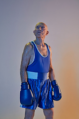 Image showing Senior man wearing sportwear boxing isolated on gradient studio background in neon light. Concept of sport, activity, movement, wellbeing. Copyspace, ad.