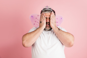 Image showing Handsome caucasian plus size male model isolated on coral pink studio background. Concept of inclusion, human emotions, facial expression