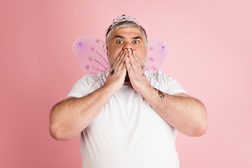 Image showing Handsome caucasian plus size male model isolated on coral pink studio background. Concept of inclusion, human emotions, facial expression