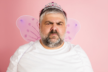 Image showing Handsome caucasian plus size male model isolated on coral pink studio background. Concept of inclusion, human emotions, facial expression