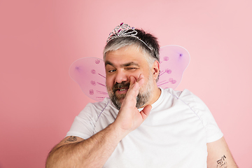 Image showing Handsome caucasian plus size male model isolated on coral pink studio background. Concept of inclusion, human emotions, facial expression