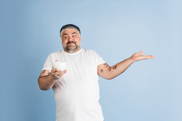 Image showing Handsome caucasian plus size male model isolated on blue studio background. Concept of inclusion, human emotions, facial expression