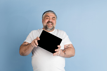 Image showing Handsome caucasian plus size male model isolated on blue studio background. Concept of inclusion, human emotions, facial expression