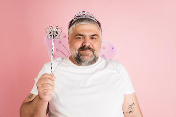 Image showing Handsome caucasian plus size male model isolated on coral pink studio background. Concept of inclusion, human emotions, facial expression