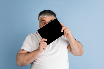 Image showing Handsome caucasian plus size male model isolated on blue studio background. Concept of inclusion, human emotions, facial expression