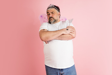 Image showing Handsome caucasian plus size male model isolated on coral pink studio background. Concept of inclusion, human emotions, facial expression