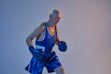 Image showing Senior man wearing sportwear boxing isolated on gradient studio background in neon light. Concept of sport, activity, movement, wellbeing. Copyspace, ad.