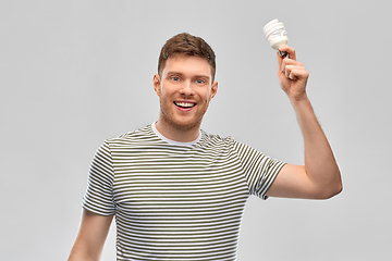 Image showing smiling young man holding lighting bulb