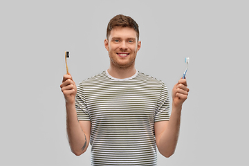 Image showing man comparing wooden and plastic toothbrush