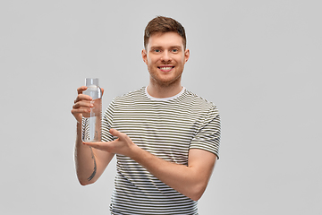 Image showing happy smiling man holding water in glass bottle