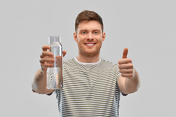 Image showing happy smiling man holding water in glass bottle