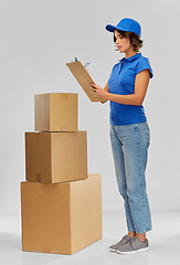 Image showing happy delivery girl with boxes and clipboard