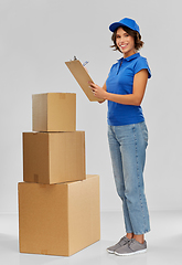 Image showing happy delivery girl with boxes and clipboard