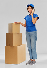 Image showing delivery woman with boxes calling on smartphone