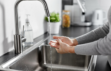 Image showing woman washing hands with liquid soap in kitchen