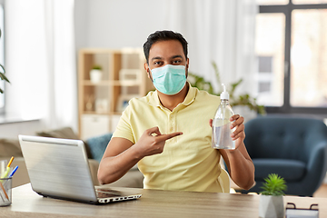 Image showing man in mask with hand sanitizer at home office