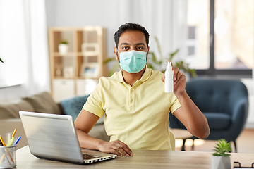 Image showing man in mask with hand sanitizer at home office