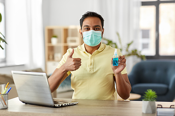 Image showing man in mask with hand sanitizer at home office