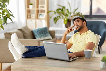 Image showing man with laptop resting feet on table at home