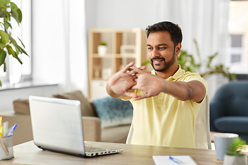 Image showing happy man with laptop stretching at home office