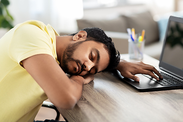 Image showing indian man sleeping on table with laptop at home