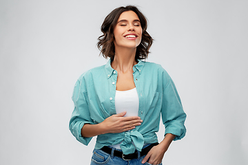 Image showing happy full young woman touching her tummy